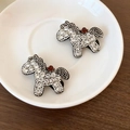 Détail d'une pince à cheveux cheval de luxe avec strass brillants et gemme rouge - Poney Blanc