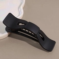 Dettaglio di un elegante fermaglio per capelli nero opaco su vassoio decorativo - Nero