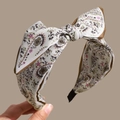 Detailed close-up of Bohemian paisley print headband with a large fabric bow and gold trim - Beige
