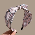 Close-up of bohemian paisley print headband with silk texture and twist knot detail - Pink