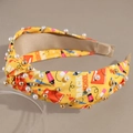 Close-up of yellow back to school knotted headband with stationery prints and pearls - Yellow
