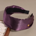 Detail of a deep purple satin headband with a golden metal logo and silk texture - Purple