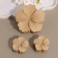 Detailed macro view of three matte morandi flower hair claws in neutral beige tones - Khaki