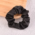 Elegant black satin scrunchie with smooth silk texture on a rustic wooden tray - Black