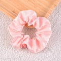 Detailed view of pink satin scrunchie with silky luster on a wooden tray - Pink