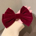 Detailed view of a wine red velvet bow hair clip held by hand showing size and texture - Wine Red Velvet