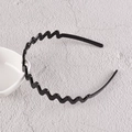 Gros plan d'un serre-tête noir ondulé en plastique avec dents antidérapantes durables - Vague moyenne / Noir