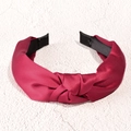 Dettaglio di cerchietto largo in raso bordeaux con nodo elegante e texture setosa - Rosso