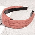 Detail of pink knitted headband featuring a top knot and chunky braided texture - Pink