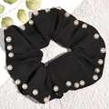 Close-up of black scrunchie with pearl embellishments on a clean textured background - Black
