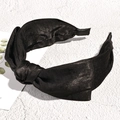 Detailed macro view of black satin fabric texture and top knot design on wide headband - Black