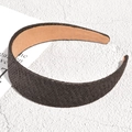Detalle de una diadema ancha de rafia trenzada en marrón oscuro con textura tejida - Negro