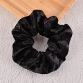 Close-up of black velvet scrunchie showing soft texture on a natural wooden tray - Black