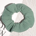 Detail view of the sage green pleated scrunchie with fine texture and stitching - Green