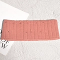 Détail d'un bandeau en tricot rose corail avec texture côtelée et pompons 3D doux - Rose