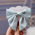 Detailed close-up of a light blue chiffon bow hair clip on a heart-shaped fashion card - Light Blue