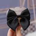 Close-up of a stylish black chiffon bow hair clip on a white jewelry display card - Black