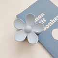 Close-up of a matte light blue flower hair claw clip on a vintage book surface - Gray