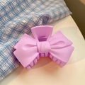 Primer plano de pinza de pelo rosa mate con forma de lazo sobre fondo minimalista - Violeta Claro