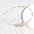 Vista dettagliata di un cerchietto in metallo dorato con nodo infinito di perle e strass - Design Infinito con Perle