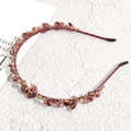 Detailed macro view of champagne crystal beads and golden alloys on a burgundy headband - Fuschia