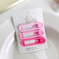 Dettaglio di tre mollette per capelli rosa opaco su cartoncino in un piatto bianco - Ellisse / Rosa