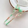 Dettaglio di un fermaglio per capelli a farfalla in acetato rosa e verde su un piatto - Verde