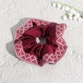 Detail eines bordeauxroten Satin-Haargummis mit gewebtem Rand und Maiglöckchen-Deko - Rot