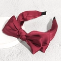 Detalle de diadema de satén burdeos con lazo grande y textura de seda brillante - Rojo