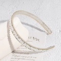 Close-up of Baroque crystal headband with rhinestone rows and golden beaded trim detailing - White