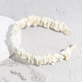 Detalle de una diadema de satén crema con elegante textura plisada y brillo suave - Blanco