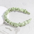Detalle de diadema de satén plisado verde claro que muestra la textura de tela brillante - Verde