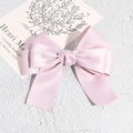 Detailopname van elegante dubbellaagse roze satijnen haarclip met een luxe strik - Roze