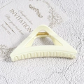 Close-up of a cream triangle claw clip with a gold spring on an invitation card - White