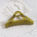 Detail of olive green triangular hair claw clip with golden spring on textured background - Green