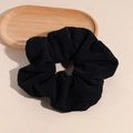 Detailed close-up of a black corduroy scrunchie with soft ribbed texture and elastic band - Black