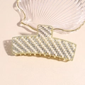 Vista macro de pinza de pelo dorada con perlas incrustadas y diamantes de imitación - Perla Blanca y Estrás