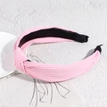 Detail showing pink pleated fabric headband with knotted design and non-slip lining - Pink