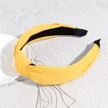 Close-up of a yellow knotted headband with fine ribbed texture on a white marble surface - Yellow