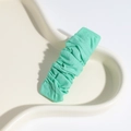 Minimalist mint green pleated fabric hair clip on a white ceramic tray display - Green