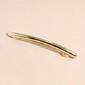 Dettaglio di un fermaglio per capelli dorato lucido su uno sfondo rosa morbido - Stile Bordo Sottile Oro Lucidato a Specchio / Oro Sottile