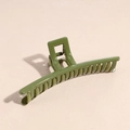 Primo piano di una pinza per capelli verde oliva lucida su uno sfondo neutro testurizzato - Quadrato Verde