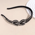 Dettaglio del cerchietto nero con cuori di cristallo scintillanti su sfondo beige - Nero