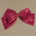 Macro detail of oversized magenta satin bow hair clip with multi-layered fabric texture - Burgundy