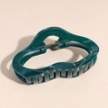 Close-up of a dark green wavy claw clip with golden metal spring on a beige surface - Cloud Green