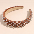 Dettaglio del cerchietto in pelle marrone con borchie a cono argento stile punk - Rosso Mattone
