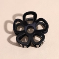Macro view of a black hollowed-out flower hair claw clip with a glossy finish - Black