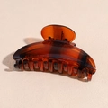 Macro detail of amber acrylic hair claw clip showing polished teeth and metal spring - Amber