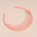 Detail eines rosa matten Wellenhaarreifens mit rutschfesten Zähnen auf beige Hintergrund - Rosa