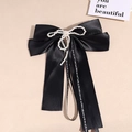 Detail of a large black satin bow hair clip with faux pearl trim and elegant white ribbons - Black (with Artificial Pearls)